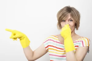 mujer cubriéndose la nariz apuntando hacia su derecha con guantes de hule