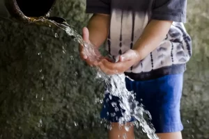 un niño lavándose las manos con el agua que cae de una tubería